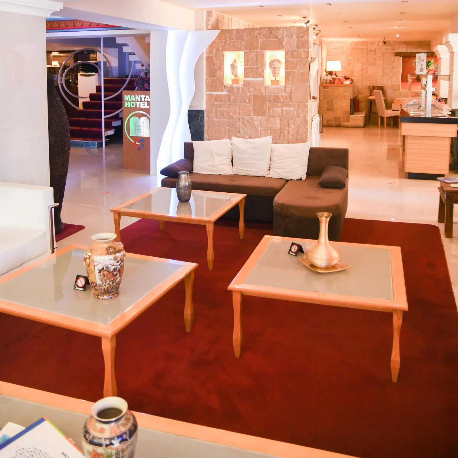 Hotelski lobi sa bež sofom i detaljima od kamena · Hotel Mantas, Lutraki