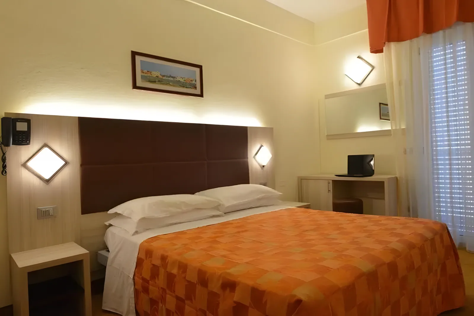 Soba sa bračnim krevetom, tamnom tablom za uzglavlje i narandžastim prekrivačem · Hotel Doge, Torre Pedrera