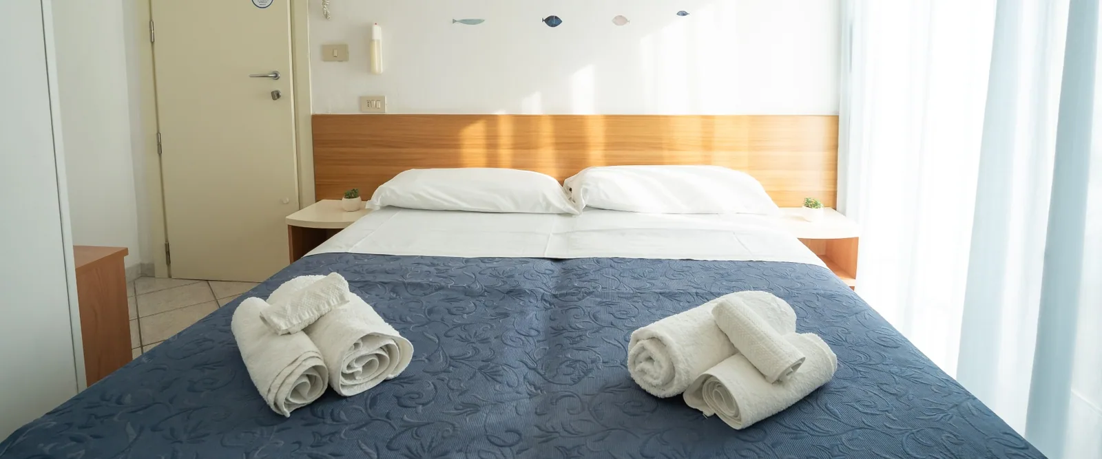 Krevet sa smotanim peškirima i uzglavljem od drveta · Hotel Kelly, Marebello