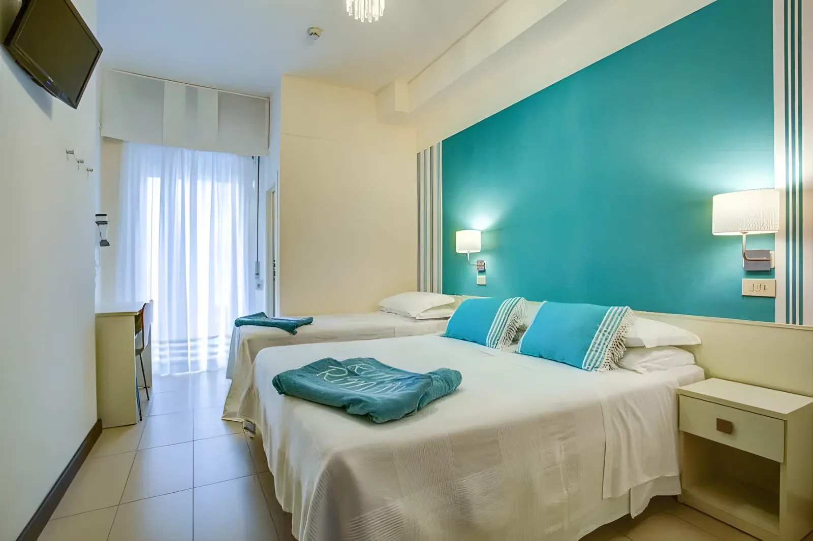 Soba sa dva kreveta, zidom u tirkiznoj boji i modernim nameštajem · Hotel Konrad, Marebello