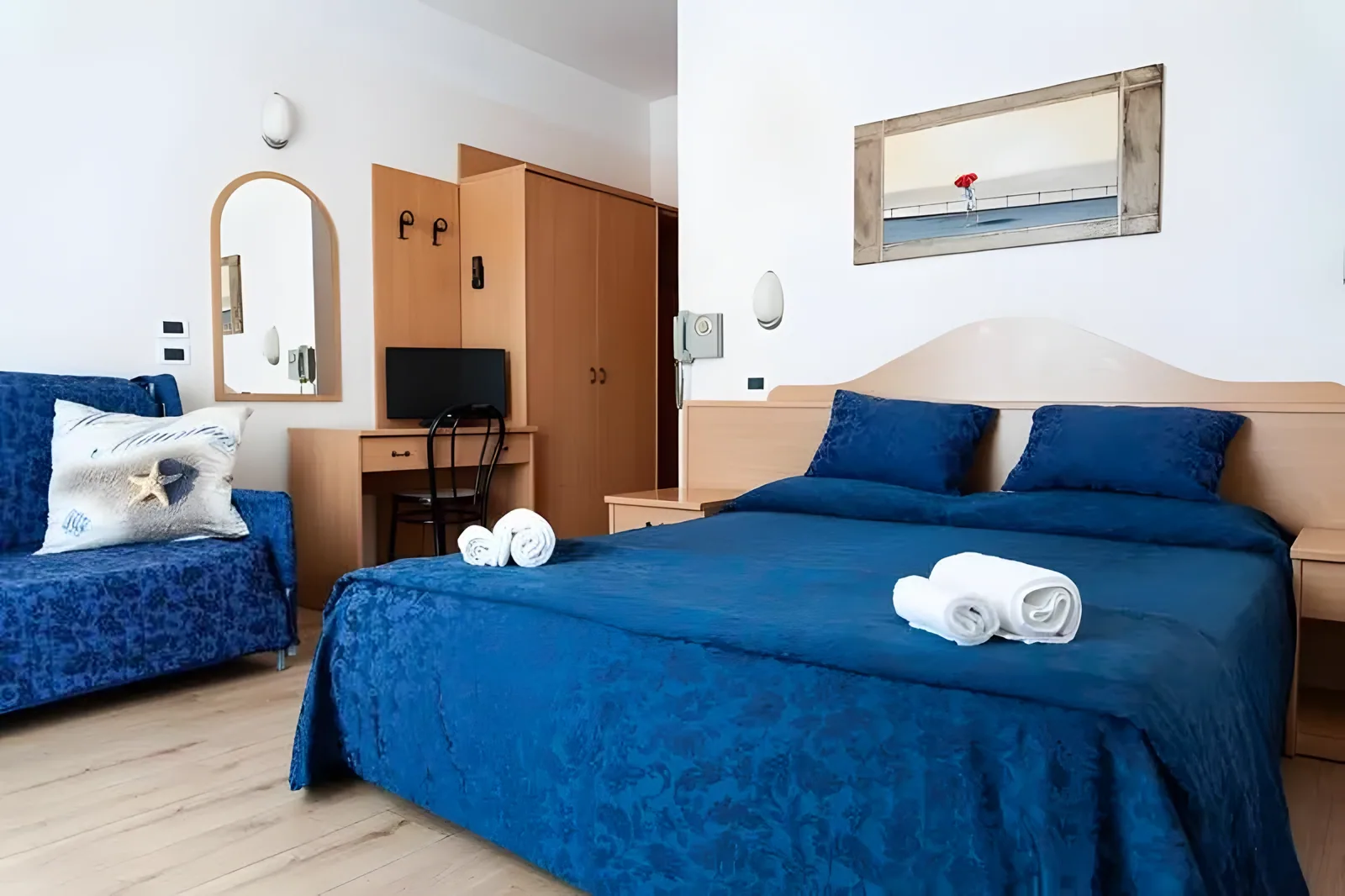Soba sa bračnim krevetom, foteljom i drvenim ormarom · Hotel Mauritus, Riccione