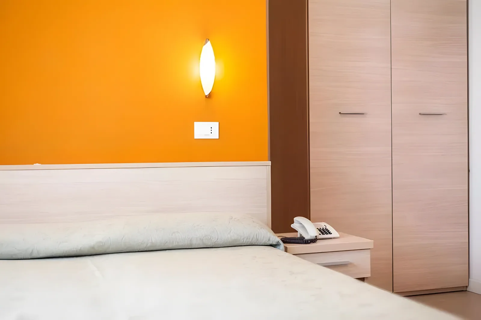 Ugao spavaće sobe sa ormarom i narandžastim dizajnom zida · Hotel Ombrosa, Bellaria - Igea Marina