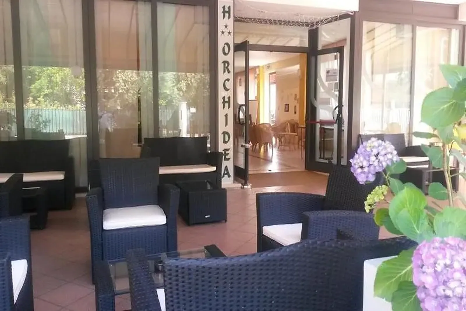 Prostor za sedenje na terasi sa pletenim nameštajem i cvećem · Hotel Orchidea, Casenatico