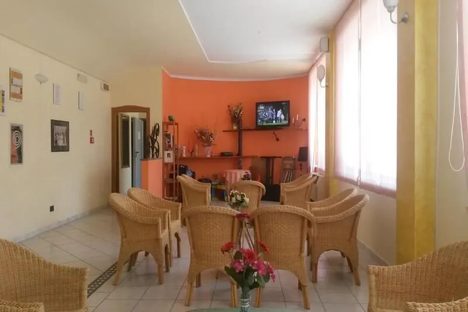 Deo za odmor sa pletenim stolicama i narandžastim akcentnim zidom · Hotel Orchidea, Casenatico