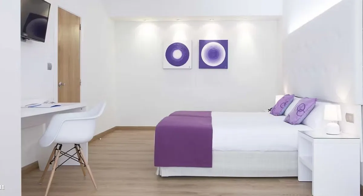 Soba sa dva kreveta, radnim stolom i belom stolicom · Hotel Albahía Alicante, Alikante