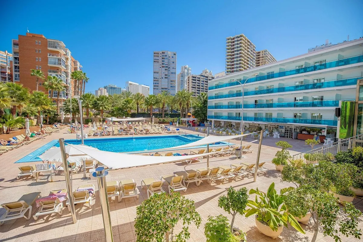 Bazen i terasa sa ležaljkama, palmama i hotelom u pozadini · Hotel Servigroup Calypso, Benidorm