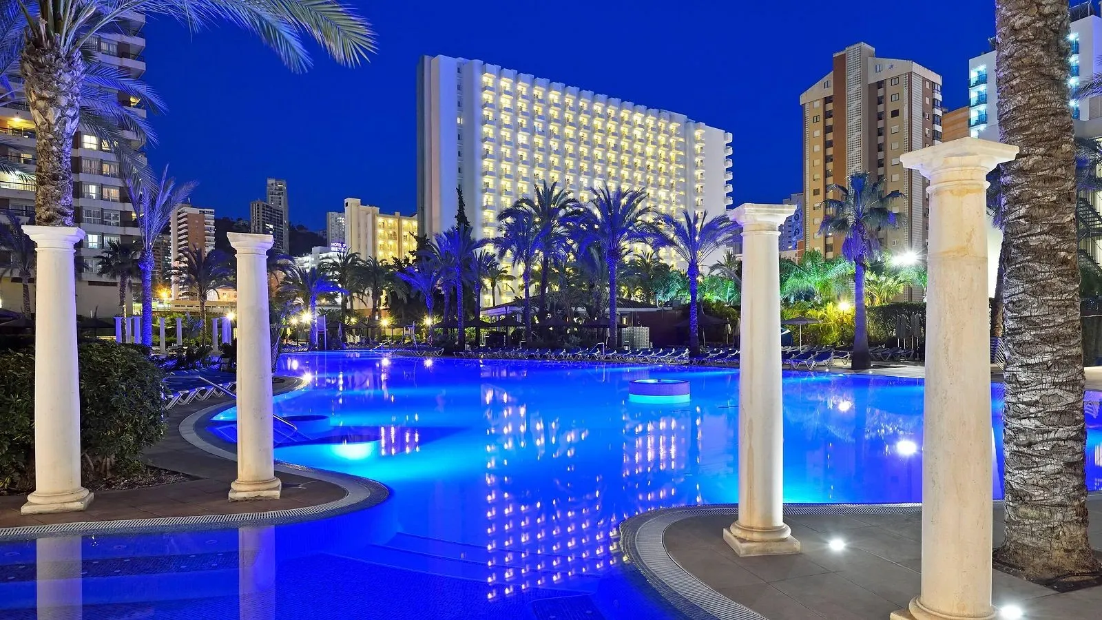 Osvetljeni bazen sa stubovima i hotelom u sumrak · Hotel Sol Pelícanos Ocas, Benidorm