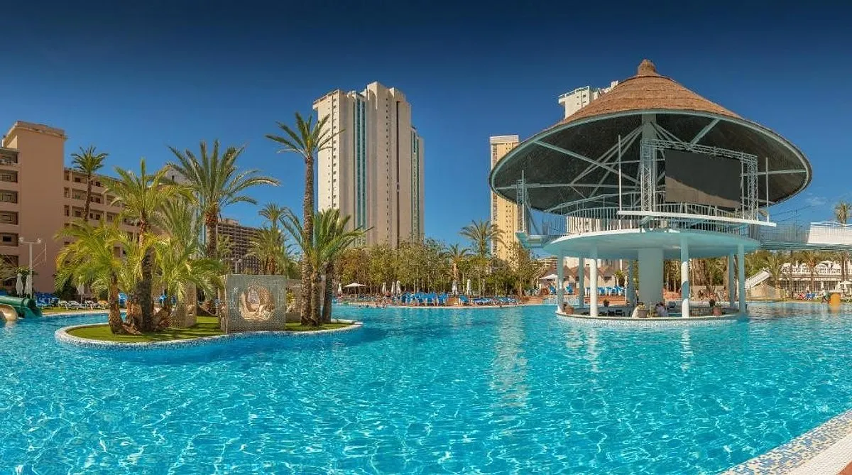 Bazen sa palmama, kolibom na sredini i visokim zgradama · Hotel Magic Tropical Splash, Finestrat